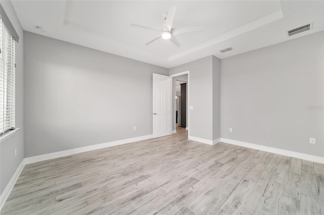 empty room featuring light wood-type flooring, baseboards, visible vents, and a ceiling fan