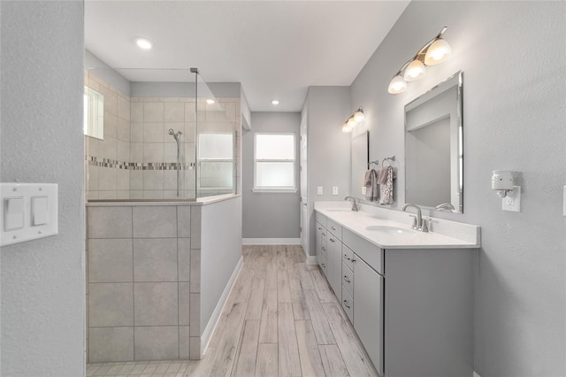 bathroom with double vanity, a sink, wood finished floors, baseboards, and walk in shower