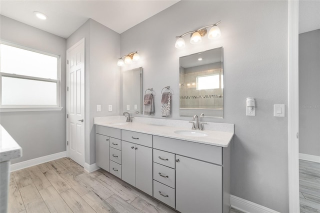 bathroom featuring double vanity, baseboards, a sink, and wood finished floors