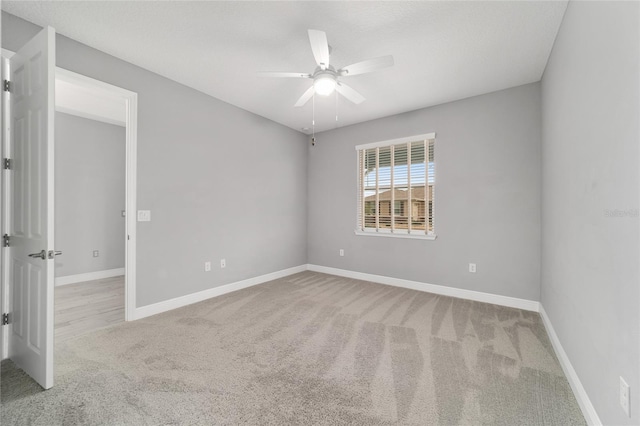 unfurnished room featuring a ceiling fan, light carpet, and baseboards