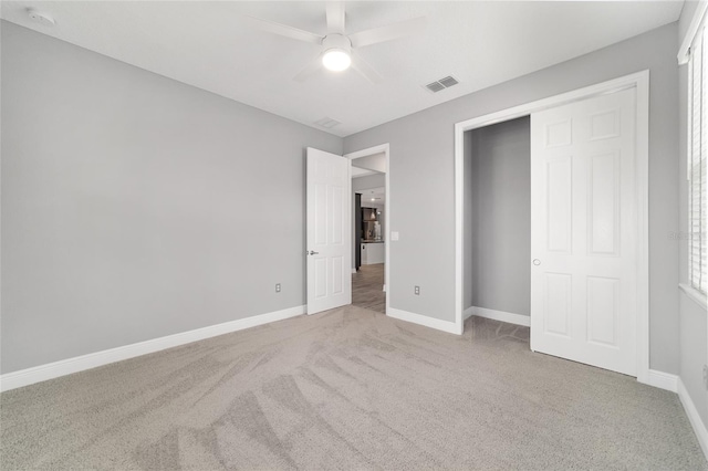 unfurnished bedroom featuring baseboards, a ceiling fan, visible vents, and light colored carpet