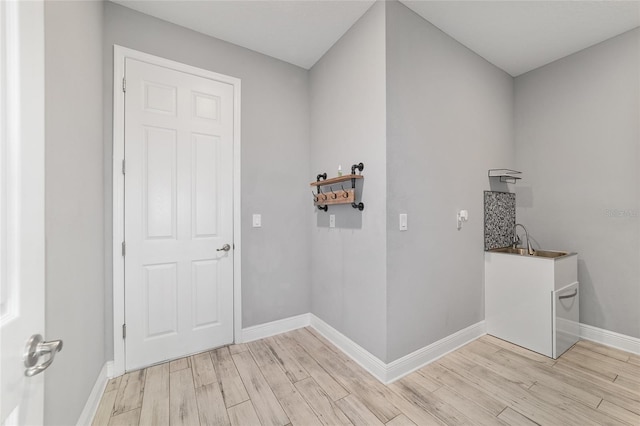 laundry area with baseboards and light wood finished floors