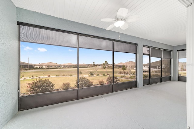 unfurnished sunroom with ceiling fan and a residential view