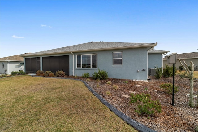 back of property with a yard, central AC unit, a sunroom, and stucco siding