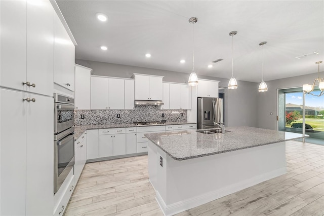 8107 SW 92nd Cir, Ocala, FL 34481 - kitchen featuring stainless steel appliances, a sink, decorative backsplash, a kitchen island with sink, and white cabinets