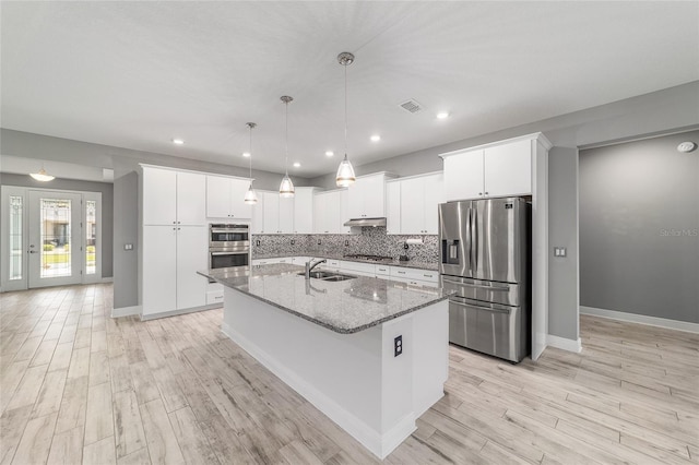 8107 SW 92nd Cir, Ocala, FL 34481 - kitchen with stainless steel appliances, an island with sink, a sink, tasteful backsplash, and light wood finished floors