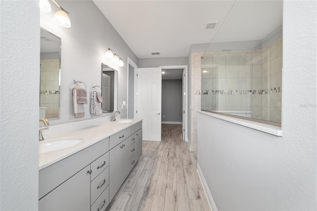 8107 SW 92nd Cir, Ocala, FL 34481 - bathroom featuring tiled shower, wood finished floors, double vanity, and baseboards