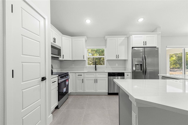 kitchen featuring stainless steel appliances, a textured ceiling, light tile patterned flooring, sink, and white cabinetry