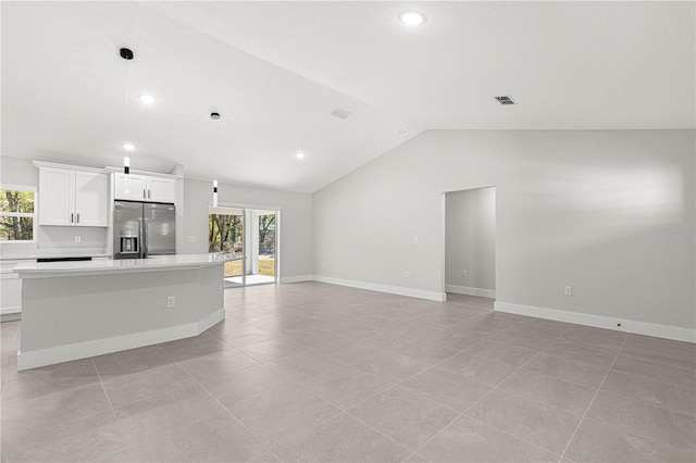 kitchen with a wealth of natural light, a center island, pendant lighting, stainless steel fridge, and white cabinets