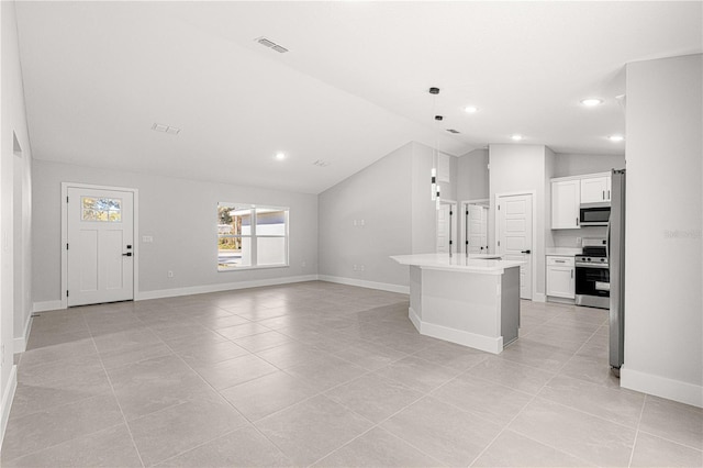 interior space with appliances with stainless steel finishes, lofted ceiling, decorative light fixtures, white cabinetry, and a kitchen island with sink