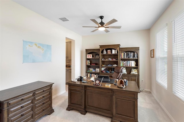 office space with light colored carpet, ceiling fan, and baseboards