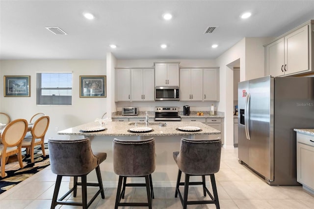 kitchen featuring light tile patterned floors, visible vents, a kitchen bar, and appliances with stainless steel finishes