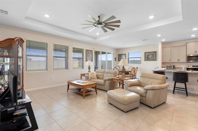 living area with ceiling fan, a raised ceiling, and recessed lighting