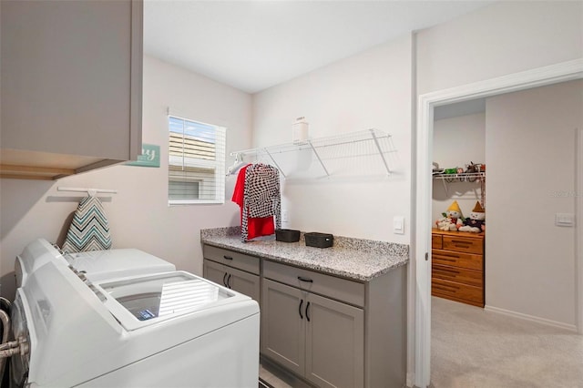 washroom with washer and dryer, cabinet space, light carpet, and baseboards