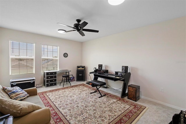 carpeted home office with ceiling fan and baseboards