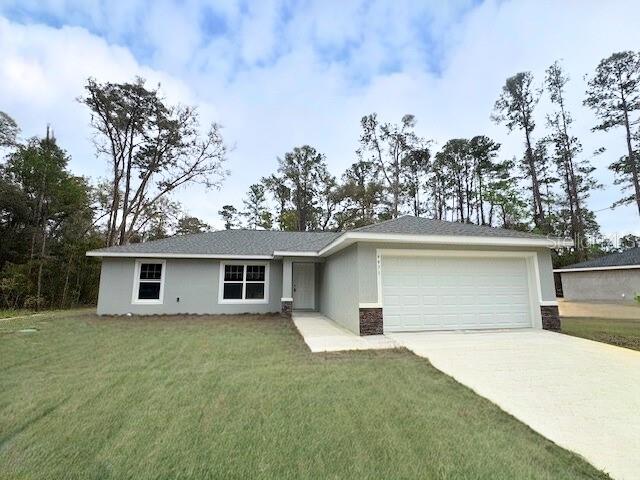 single story home with stucco siding, an attached garage, concrete driveway, and a front yard