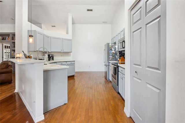 kitchen with sink, a breakfast bar, stainless steel appliances, light hardwood / wood-style floors, and kitchen peninsula