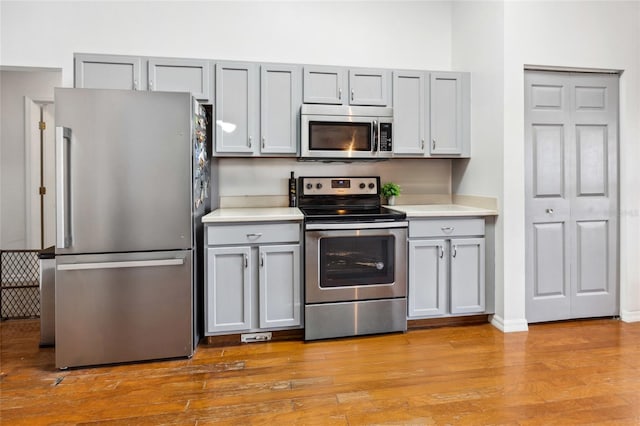 kitchen featuring stainless steel appliances, light hardwood / wood-style flooring, and gray cabinetry