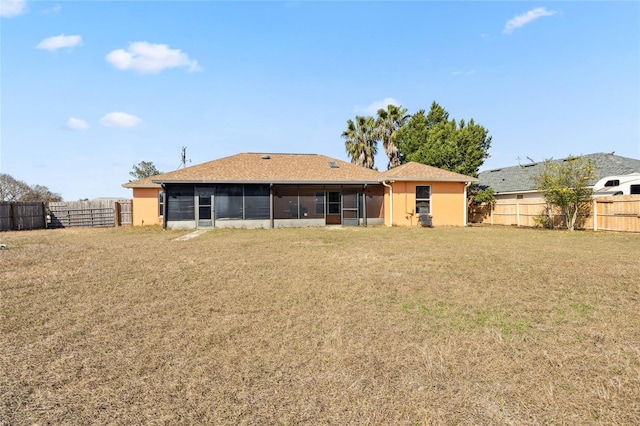 rear view of property featuring a sunroom and a lawn