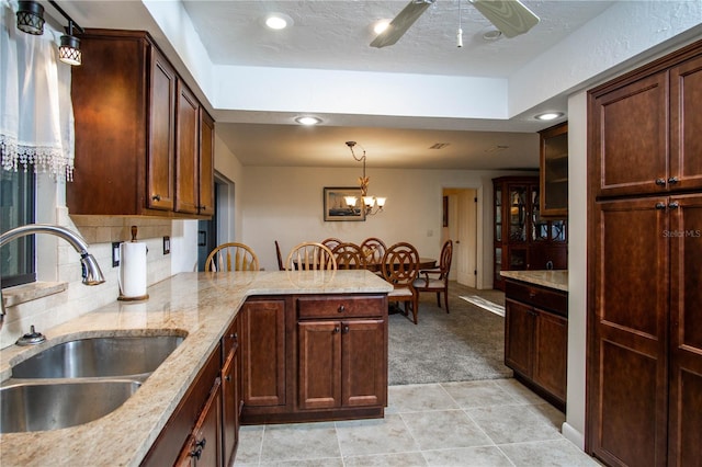 kitchen featuring light colored carpet, ceiling fan, a peninsula, a sink, and backsplash