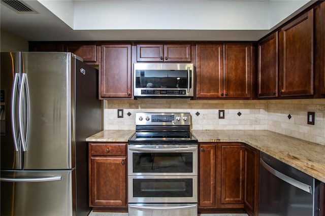 kitchen with light stone countertops, visible vents, stainless steel appliances, and decorative backsplash