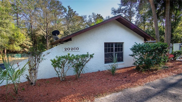 view of side of property featuring fence and stucco siding