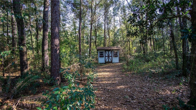 exterior space with an outbuilding, a storage unit, and a wooded view