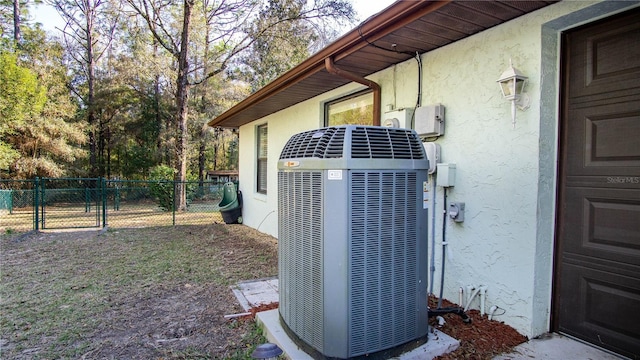 details featuring a gate, fence, cooling unit, and stucco siding