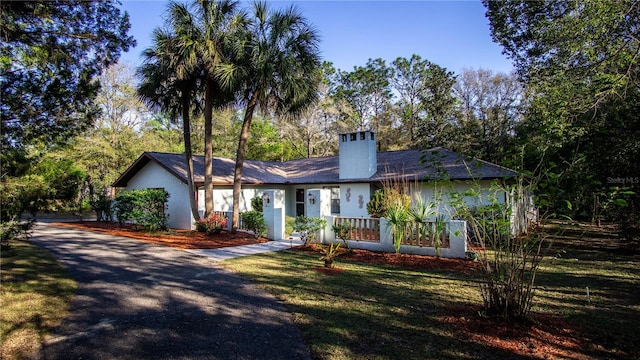 ranch-style home featuring stucco siding, a chimney, and a front yard