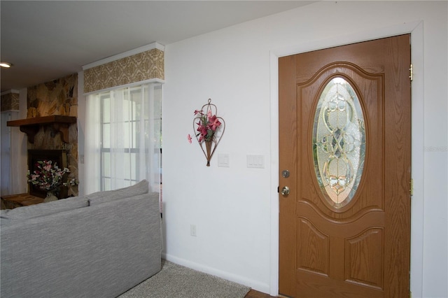 carpeted foyer featuring a fireplace and baseboards