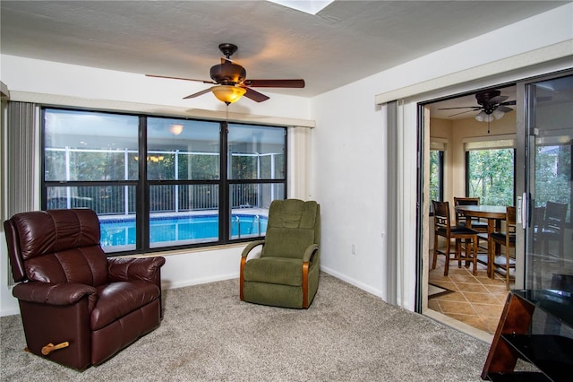 sitting room with tile patterned flooring, carpet, baseboards, and a ceiling fan