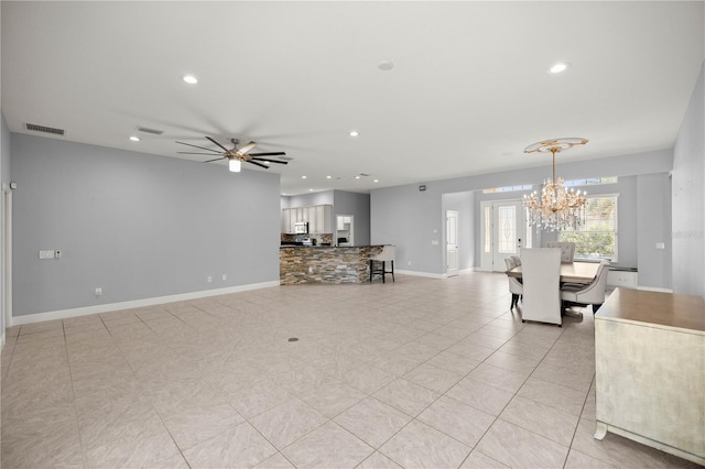 unfurnished living room featuring ceiling fan with notable chandelier