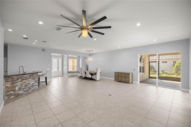 unfurnished living room with sink, ceiling fan with notable chandelier, and light tile patterned floors