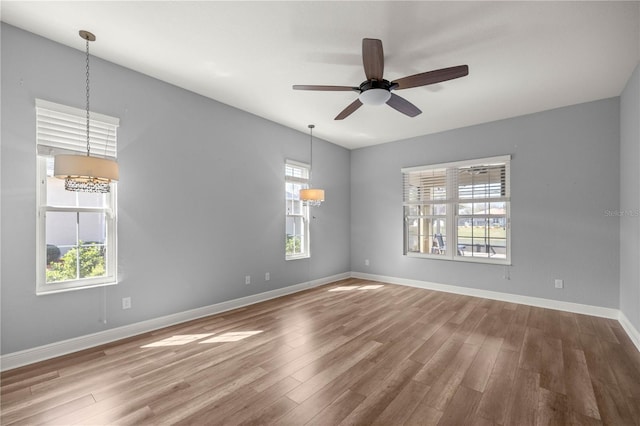 empty room with ceiling fan, wood-type flooring, and a wealth of natural light