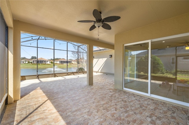 unfurnished sunroom with a water view and ceiling fan