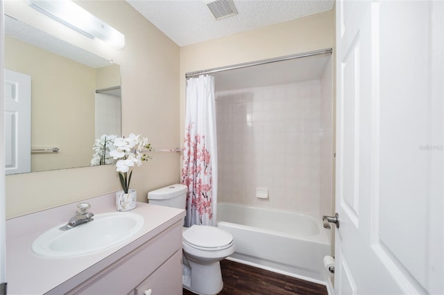 full bathroom with shower / tub combo with curtain, hardwood / wood-style floors, vanity, a textured ceiling, and toilet