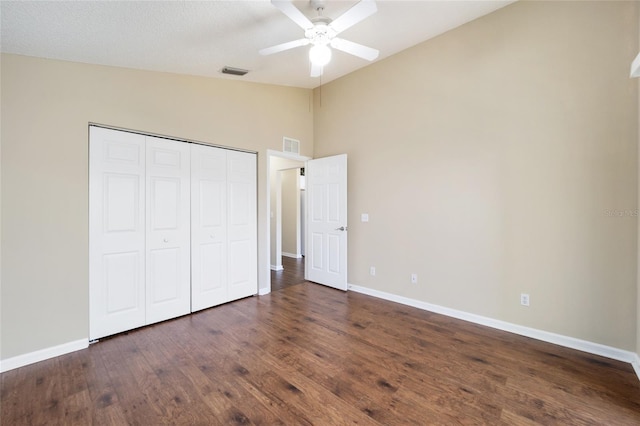 unfurnished bedroom with dark wood-type flooring, ceiling fan, lofted ceiling, and a closet