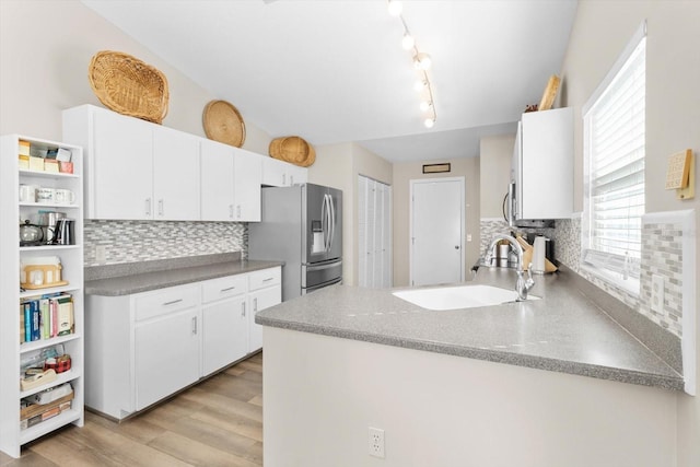 kitchen featuring sink, white cabinets, backsplash, stainless steel refrigerator with ice dispenser, and light hardwood / wood-style flooring