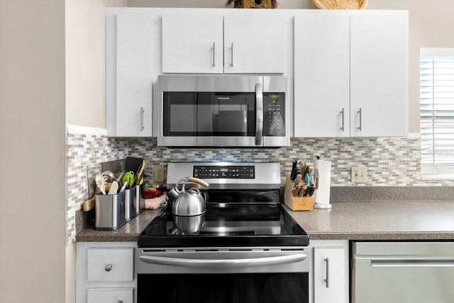 kitchen with appliances with stainless steel finishes, white cabinets, and backsplash