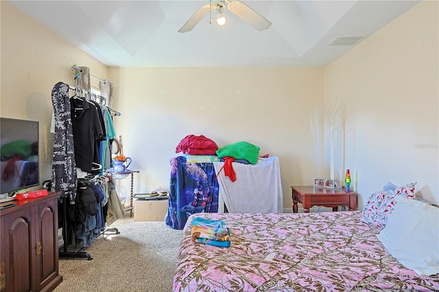 carpeted bedroom featuring a tray ceiling and ceiling fan