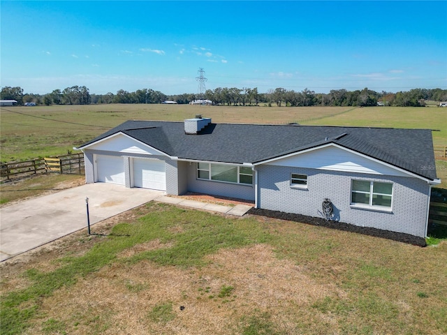 ranch-style house featuring a rural view, a garage, and a front lawn