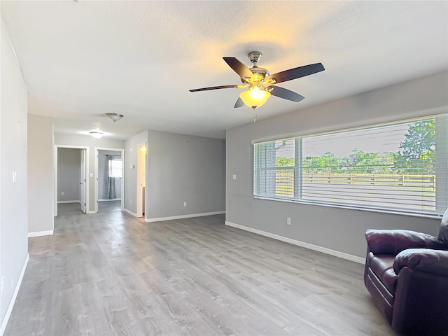 living room with ceiling fan, plenty of natural light, and light hardwood / wood-style flooring