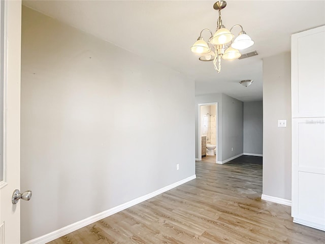 empty room with a notable chandelier and light hardwood / wood-style flooring
