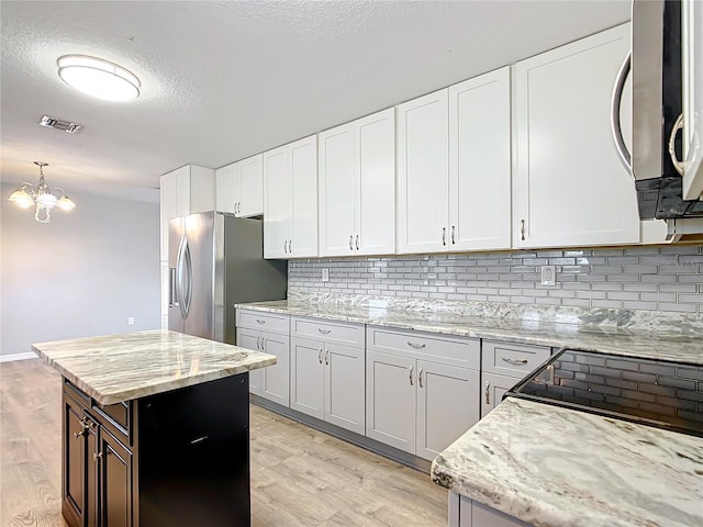 kitchen featuring white cabinetry, appliances with stainless steel finishes, light wood-type flooring, and decorative backsplash