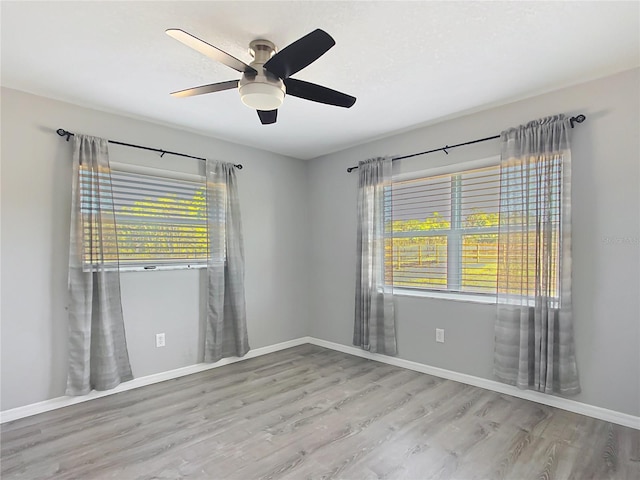spare room featuring ceiling fan, a healthy amount of sunlight, and light wood-type flooring