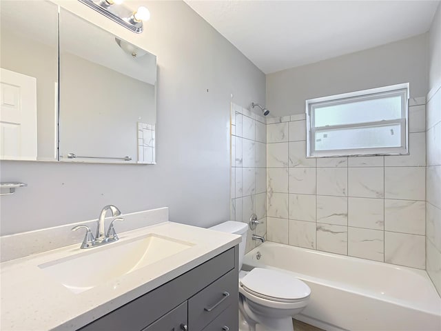full bathroom featuring tiled shower / bath combo, vanity, and toilet