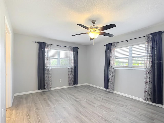 empty room with ceiling fan, a textured ceiling, and light wood-type flooring