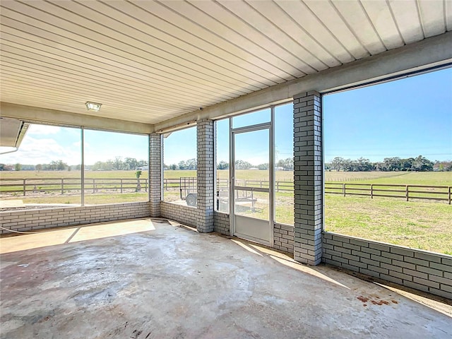 unfurnished sunroom featuring a wealth of natural light and a rural view