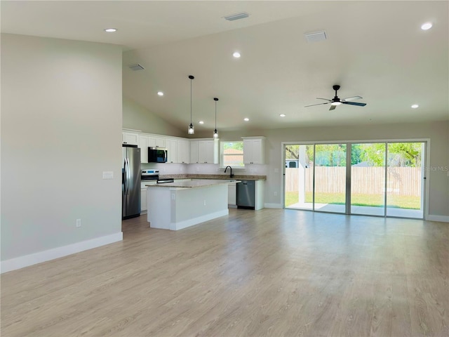 kitchen featuring open floor plan, stainless steel appliances, a kitchen island, recessed lighting, and baseboards