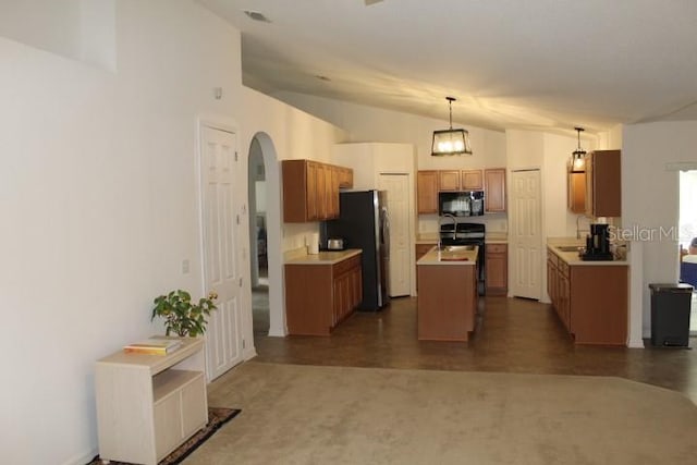 kitchen with pendant lighting, sink, lofted ceiling, appliances with stainless steel finishes, and a kitchen island with sink